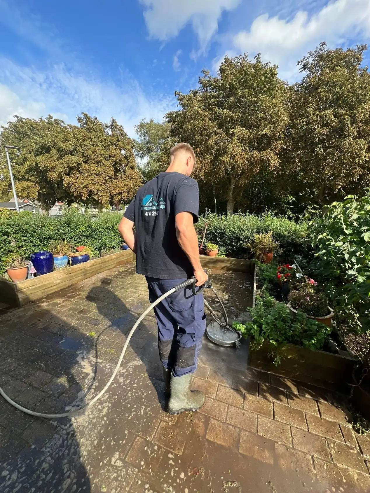 Medarbejder renser en terrasse med fladerenser